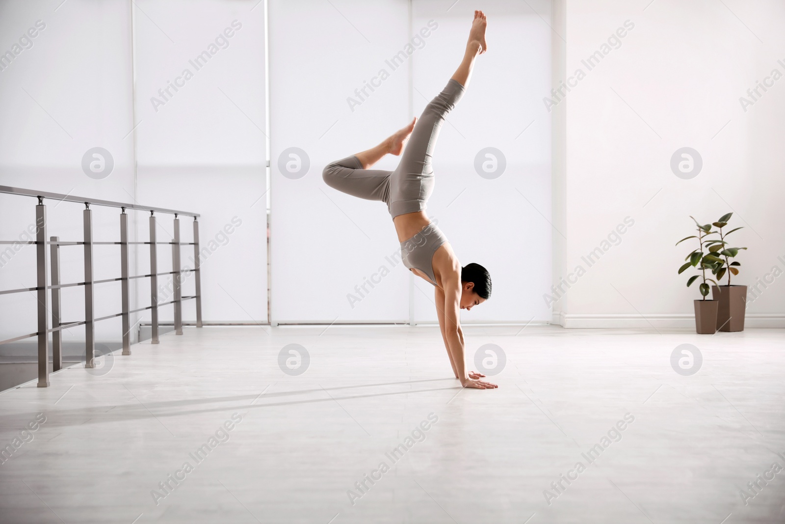 Photo of Young woman practicing downward facing tree asana in yoga studio. Adho Mukha Vrksasana pose