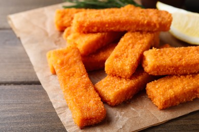 Photo of Fresh breaded fish fingers served on wooden table, closeup