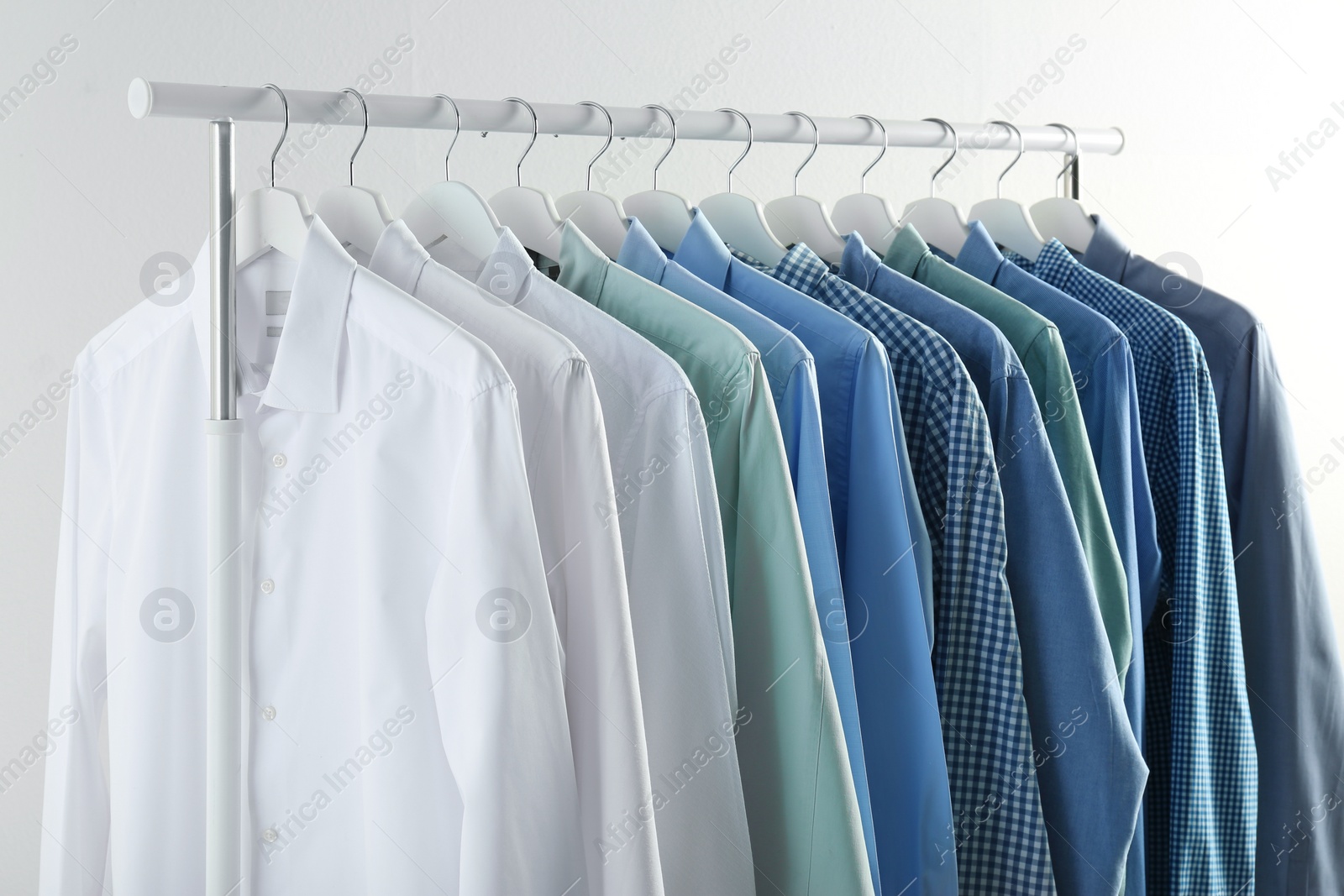 Photo of Men's clothes hanging on wardrobe rack against white background