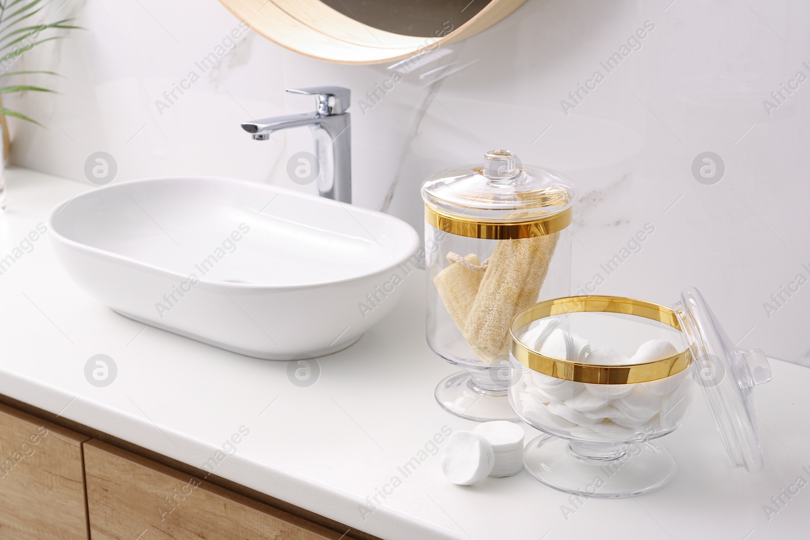 Photo of Glass jars with cotton pads and loofahs on table in bathroom