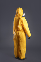 Photo of Woman wearing chemical protective suit on grey background. Virus research