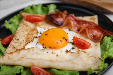 Photo of Delicious crepe with egg on plate, closeup. Breton galette