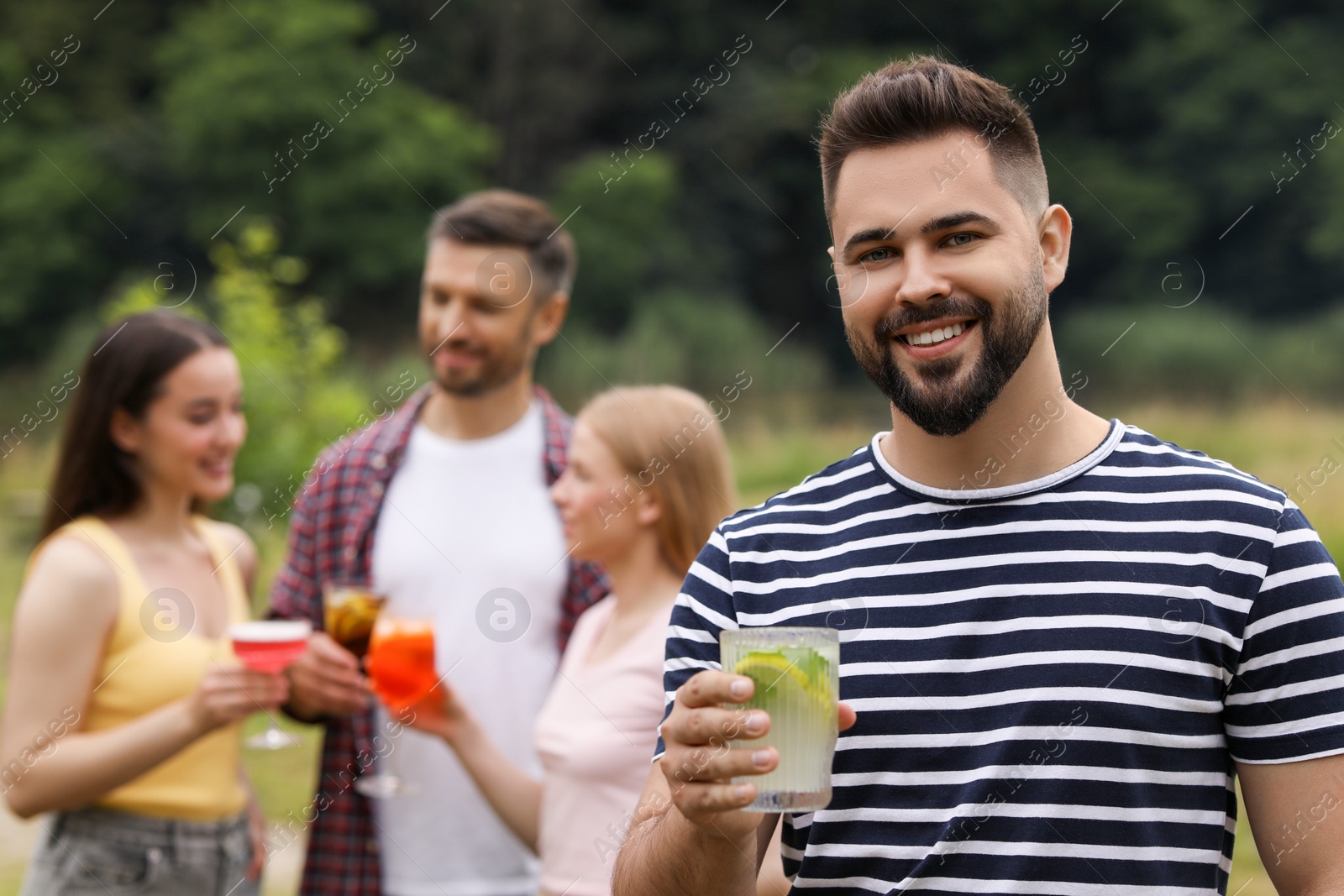 Photo of Friends having cocktail party outdoors. Happy man with glass of drink, selective focus