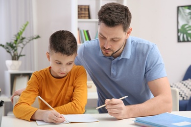 Photo of Dad helping his son with homework in room