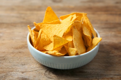 Tasty mexican nachos chips in bowl on wooden table