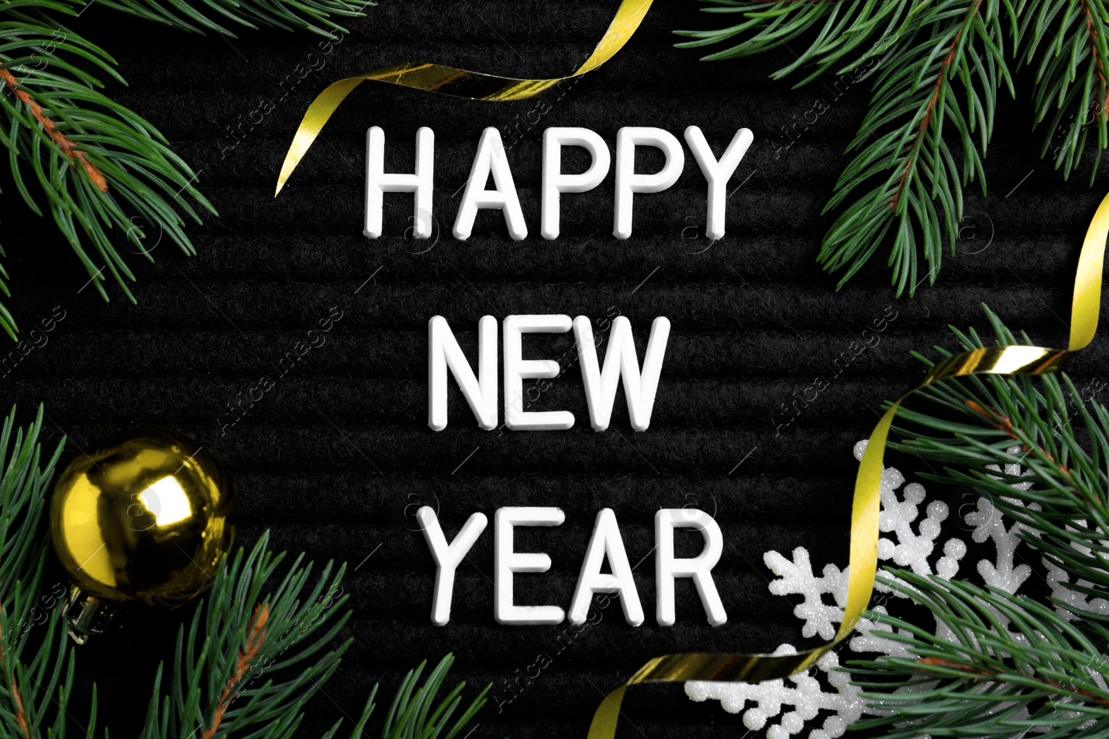 Photo of Happy New Year greeting card. Phrase made with letters and decor on black background, flat lay