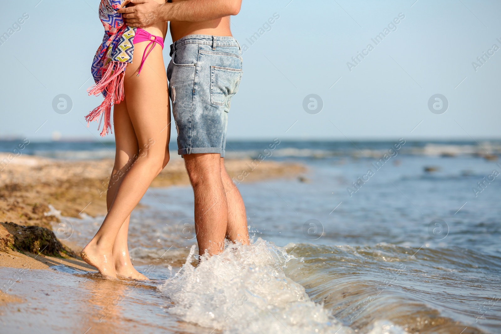 Photo of Young couple spending time together on beach, focus on legs