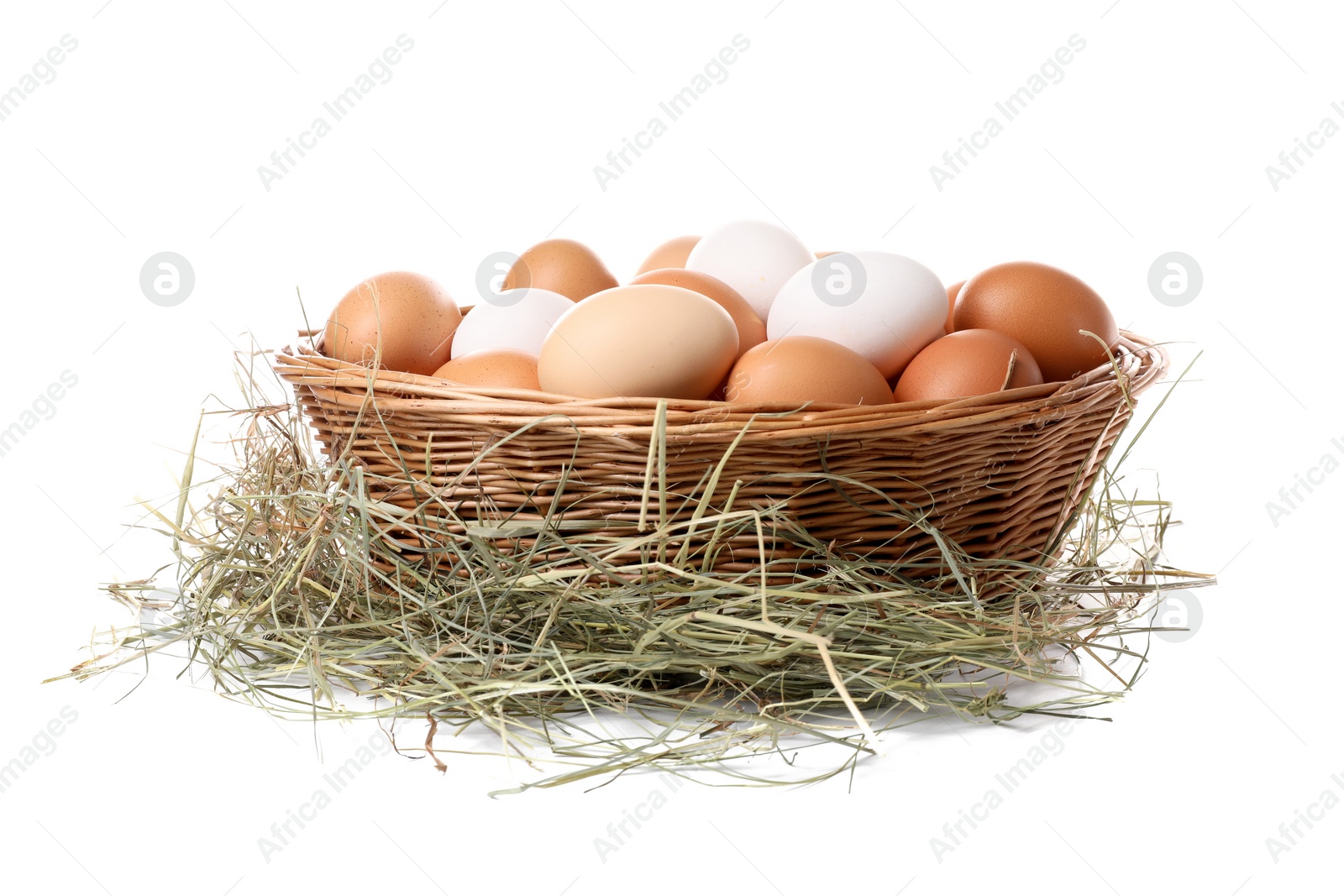 Photo of Fresh chicken eggs in wicker basket and dried hay isolated on white