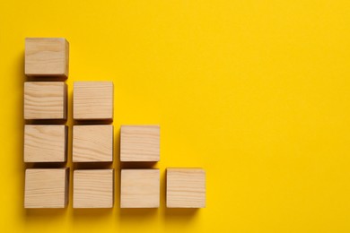 Photo of Many wooden cubes and space for text on yellow background, flat lay. Management concept