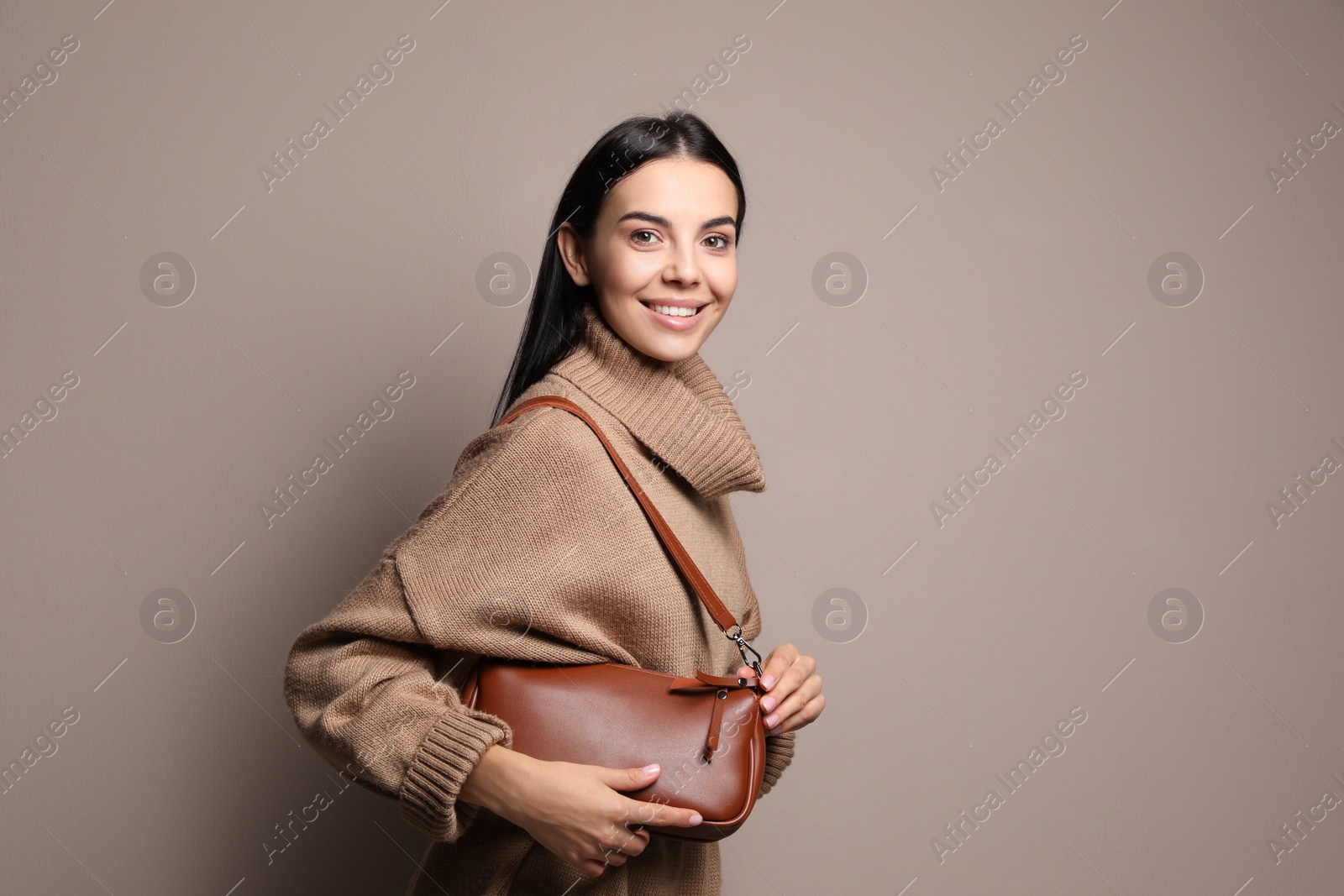 Photo of Fashionable young woman with stylish bag on beige background