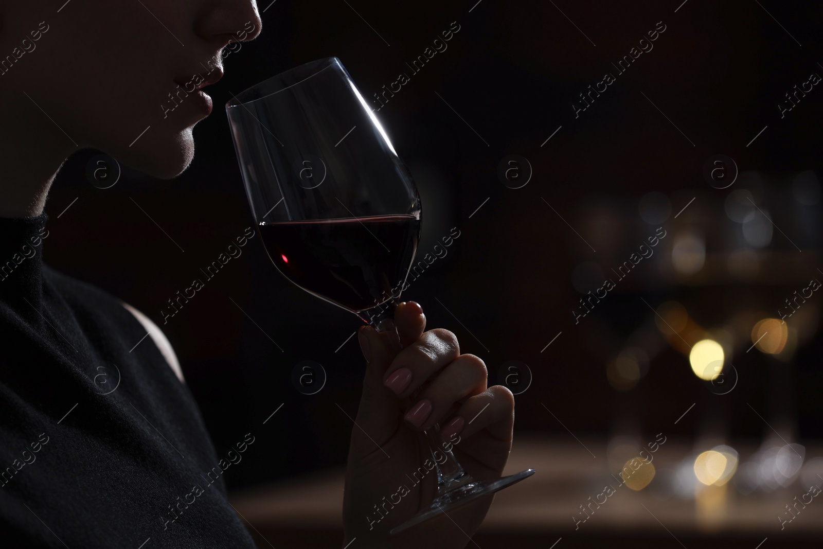 Photo of Woman with glass of red wine against blurred background, closeup. Space for text