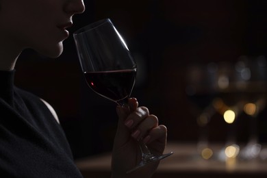 Photo of Woman with glass of red wine against blurred background, closeup. Space for text