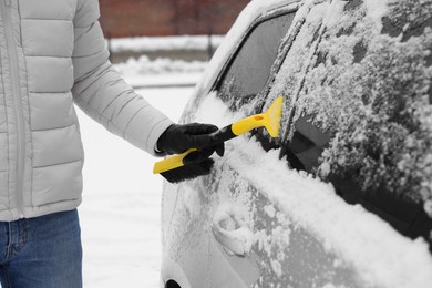 Photo of Man cleaning snow from car outdoors, closeup