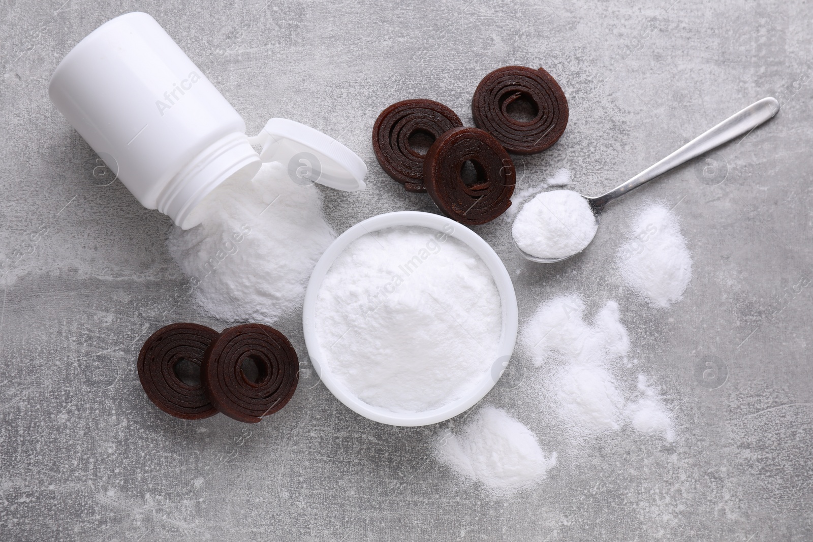 Photo of Sweet fructose powder and fruit leather rolls on light grey table, flat lay