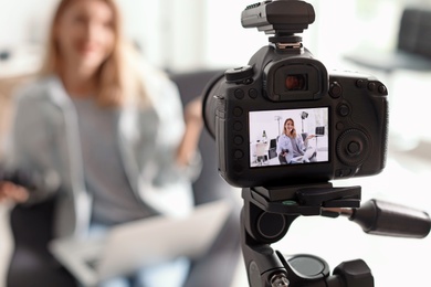 Photo of Photo blogger recording video indoors, selective focus on camera display. Space for text