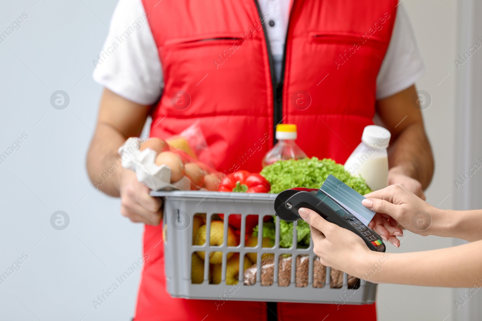 Photo of Customer using bank terminal to pay for food delivery indoors, closeup