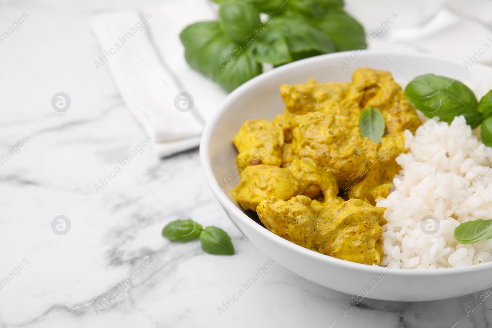 Photo of Delicious rice and chicken with curry sauce on white marble table, closeup. Space for text