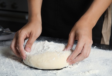 Photo of Woman making dough for pastry on table