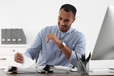 Happy businessman working with documents at table in office