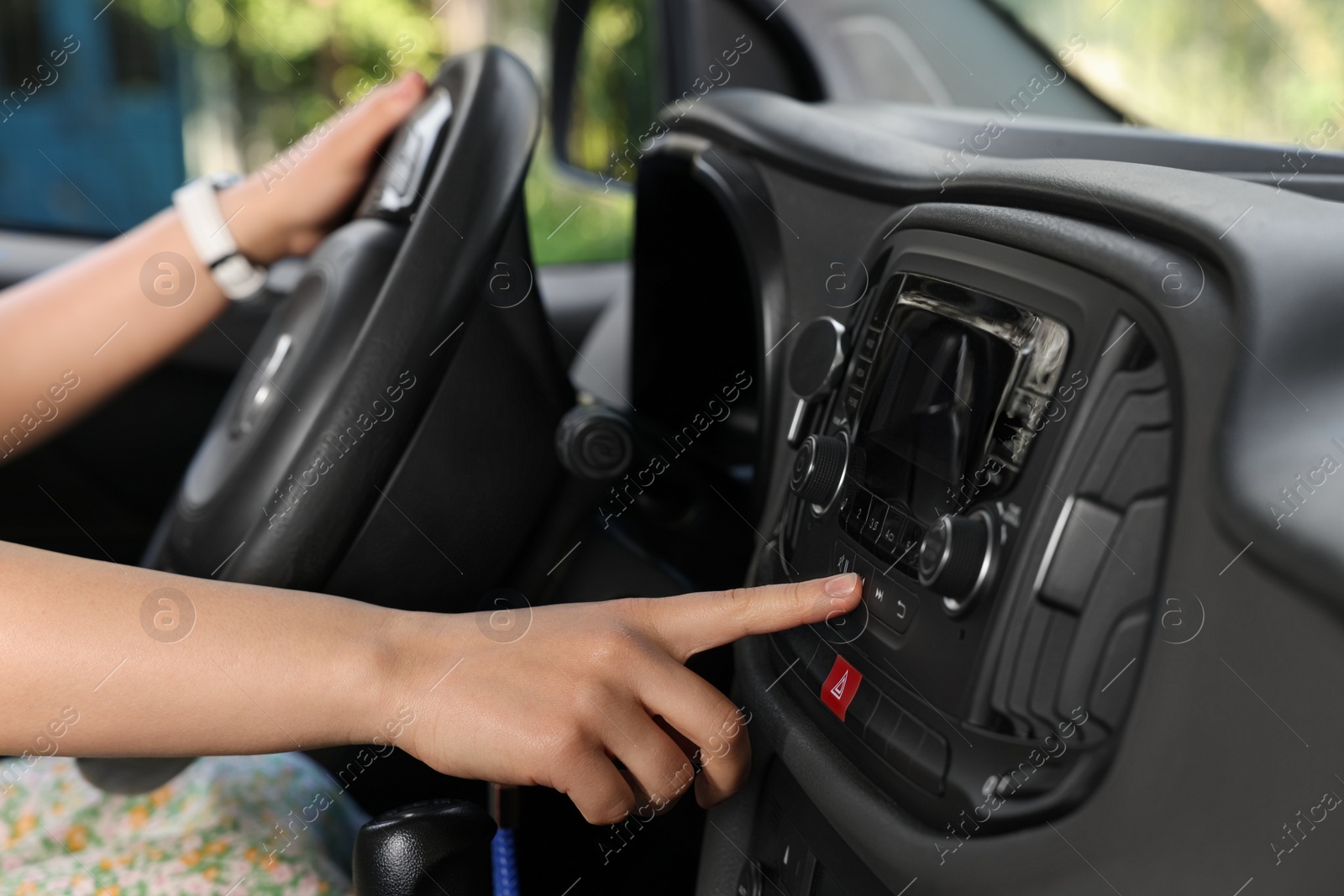 Photo of Choosing favorite radio. Woman pressing button on vehicle audio in car, closeup