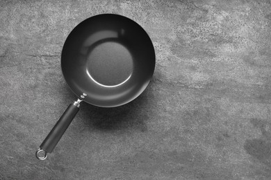Photo of Empty iron wok on grey textured table, top view. Space for text