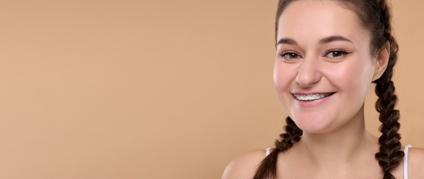 Image of Smiling woman with braces on beige background. Banner design with space for text