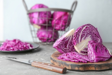 Photo of Fresh red cabbage, knife and cutting board on kitchen table