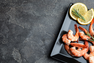 Photo of Delicious cooked shrimps with rosemary and lemon on grey table, top view. Space for text