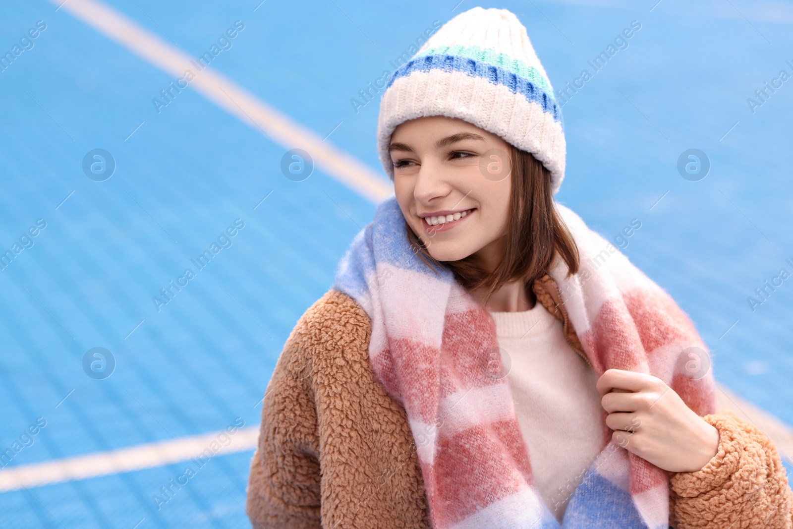 Photo of Beautiful woman in warm scarf and hat outdoors, space for text