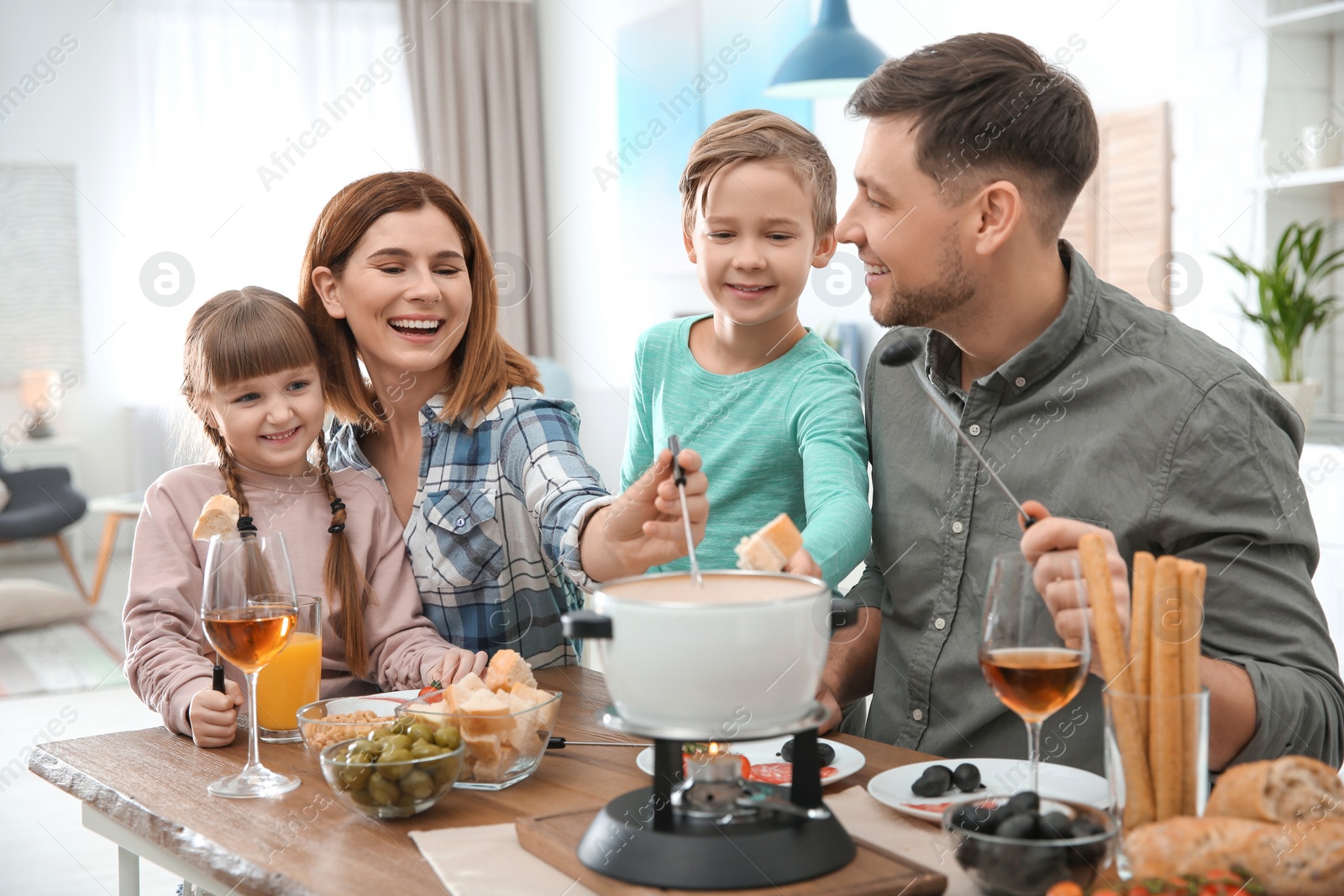 Photo of Happy family enjoying fondue dinner at home