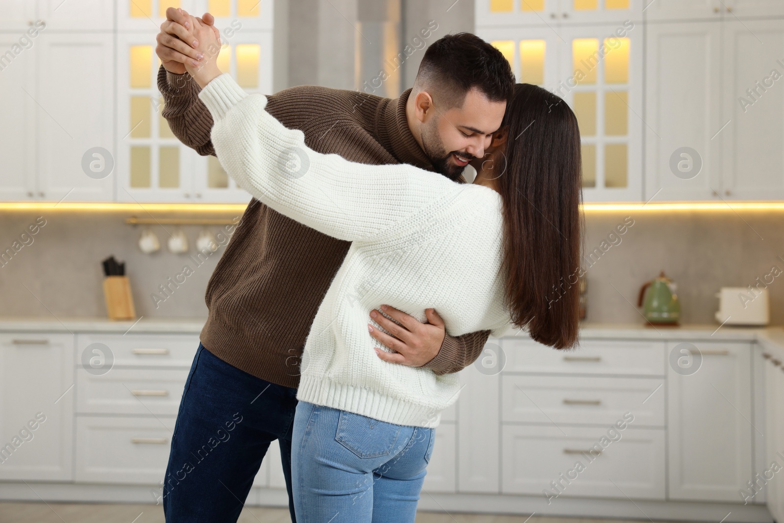 Photo of Affectionate young couple dancing in light kitchen