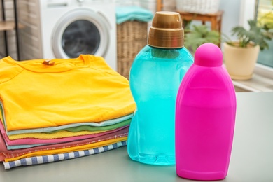 Stack of clean clothes and bottles with detergents on table in bathroom