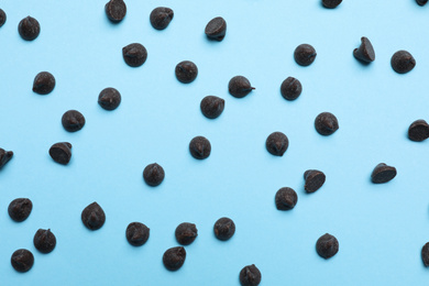 Photo of Delicious dark chocolate chips on light blue background, top view