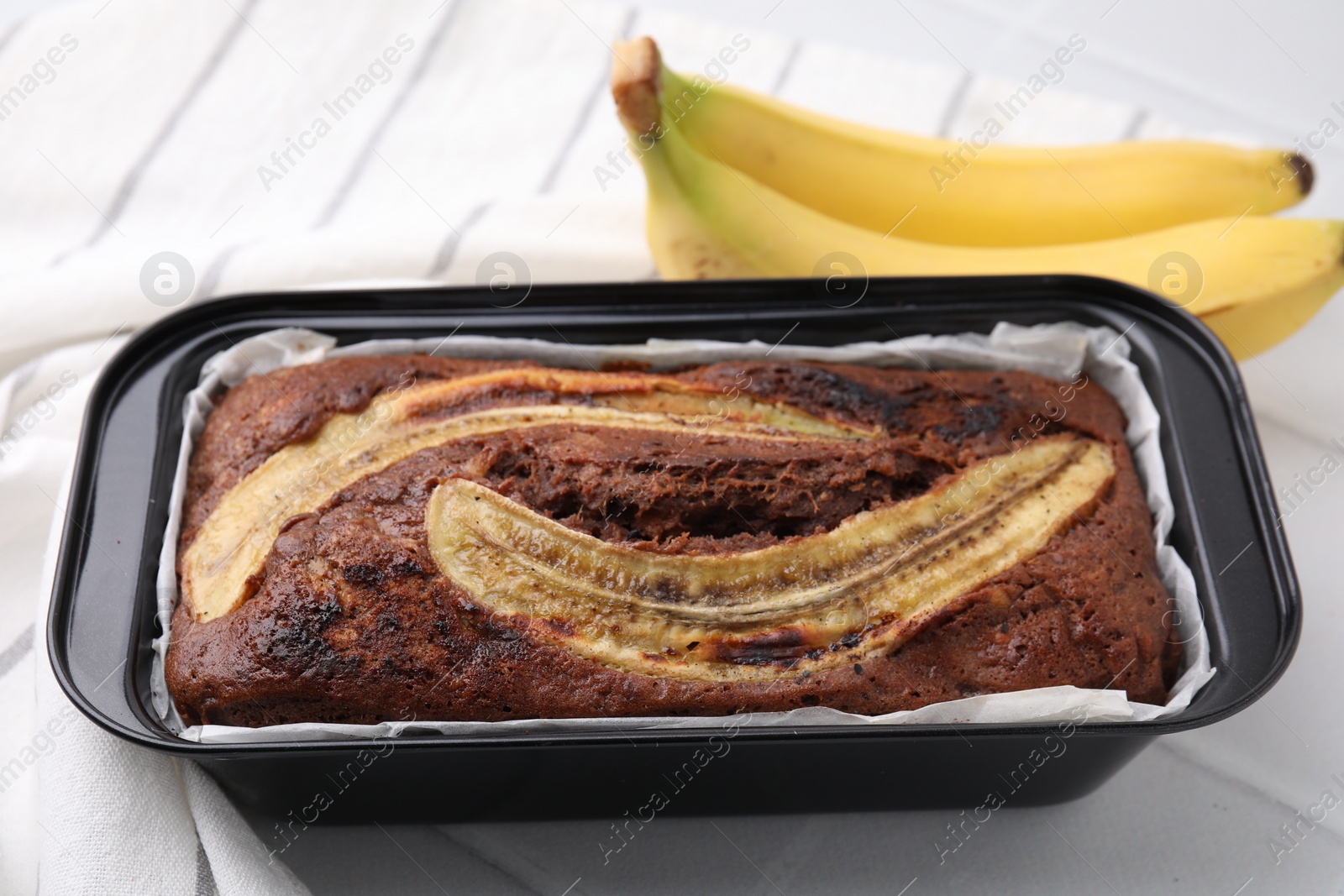 Photo of Delicious banana bread and fresh fruits on white tiled table, closeup