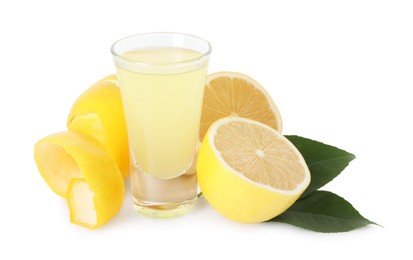 Photo of Shot glass with tasty limoncello liqueur, lemons and green leaves isolated on white