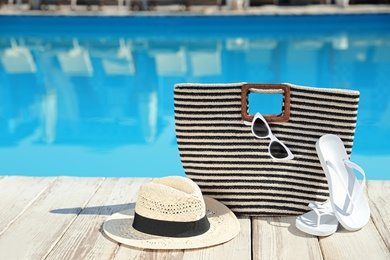 Beach accessories on wooden deck near outdoor swimming pool, space for text