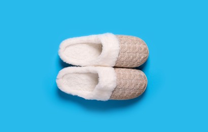 Pair of beautiful soft slippers on light blue background, top view