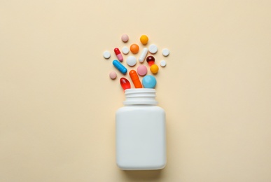 Photo of Bottle with different pills on color background, flat lay