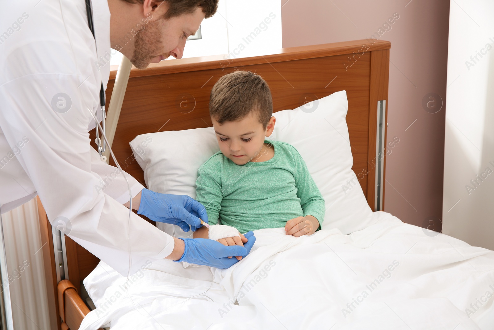 Photo of Doctor adjusting intravenous drip for little child in hospital