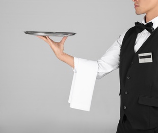 Photo of Waiter holding metal tray on grey background