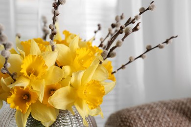 Photo of Bouquet of beautiful yellow daffodils and willow twigs in vase on blurred background, closeup