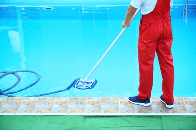 Photo of Male worker cleaning outdoor pool with underwater vacuum