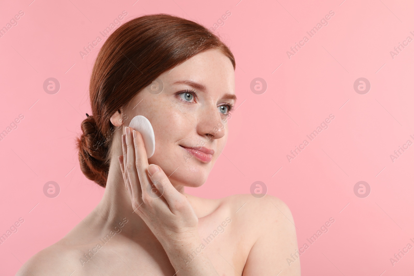 Photo of Beautiful woman with freckles wiping face on pink background