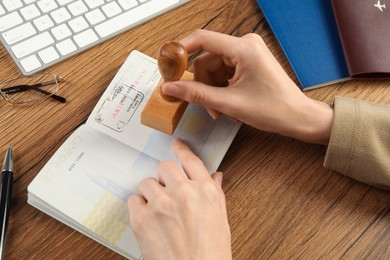 Photo of Moldova, Ceadir-Lunga - June 13, 2022: Woman stamping visa page in passport at wooden table, closeup