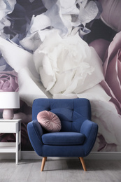 Photo of Comfortable armchair near wall with floral wallpaper. Stylish living room interior