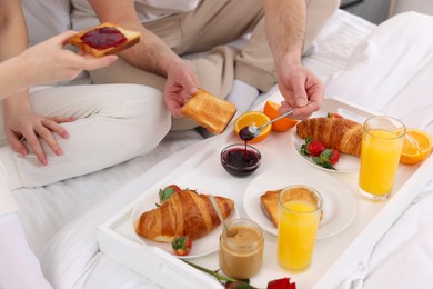 Photo of Couple eating tasty breakfast on bed, closeup