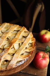 Photo of Delicious traditional apple pie on wooden stand, closeup