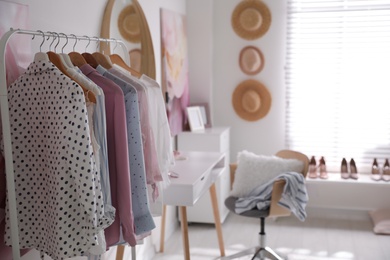 Photo of Dressing room interior with stylish makeup table, clothes and accessories