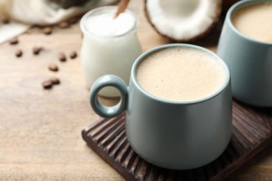 Photo of Delicious coffee with organic coconut oil on wooden table