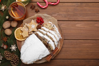Photo of Traditional Christmas Stollen with icing sugar on wooden table, flat lay. Space for text